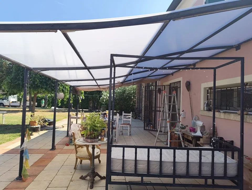 Steel pergola with shade cloth and roof, seen from the yard