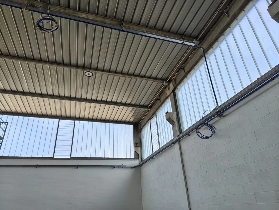 Overhead compressed air ring main installed under the warehouse roof, with hose reels hanging from it