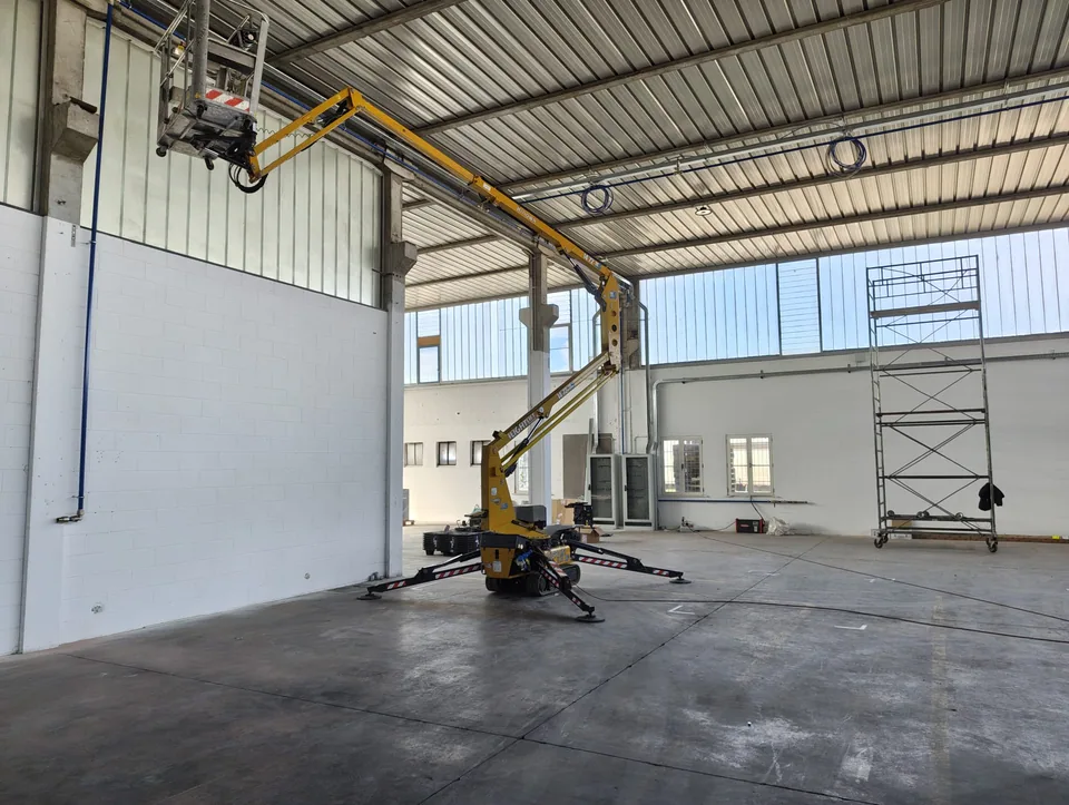 Warehouse during the work, with an aerial platform positioned under the line
