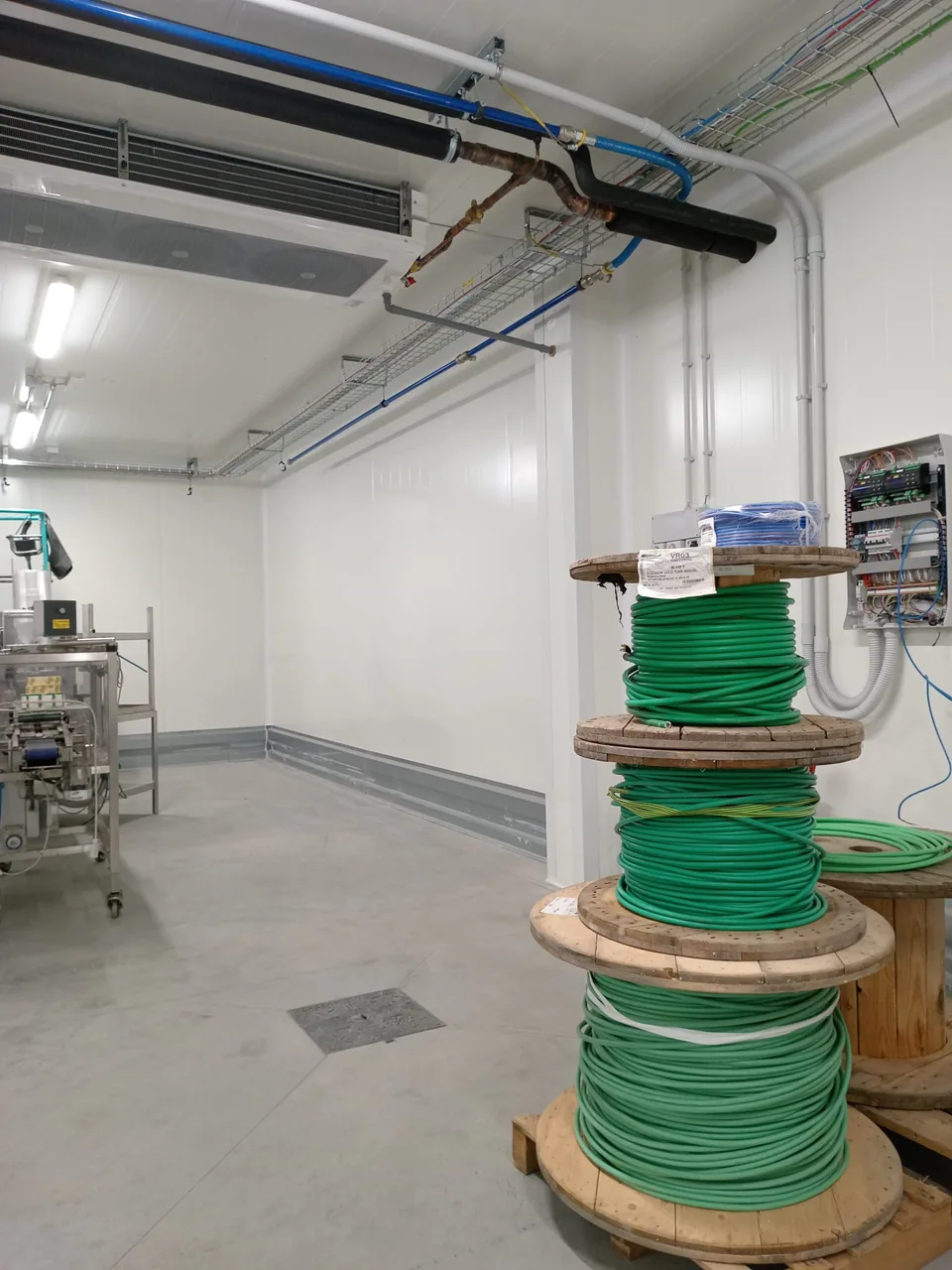 Room with pipework on the ceiling and cable drums waiting to be installed