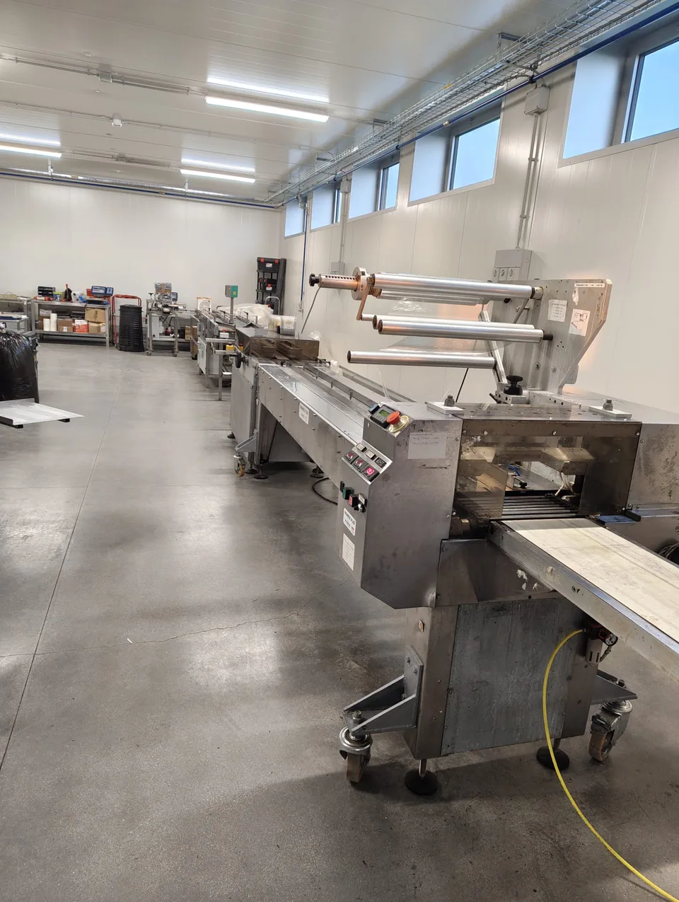 Linea di confezionamento installata in sala lavorazione, con bobine di film in alto