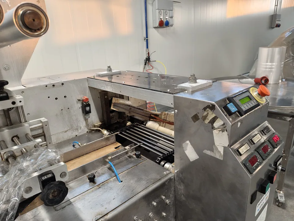 Confezionatrice flowpack aperta sul gruppo di saldatura, con quadro comandi a lato