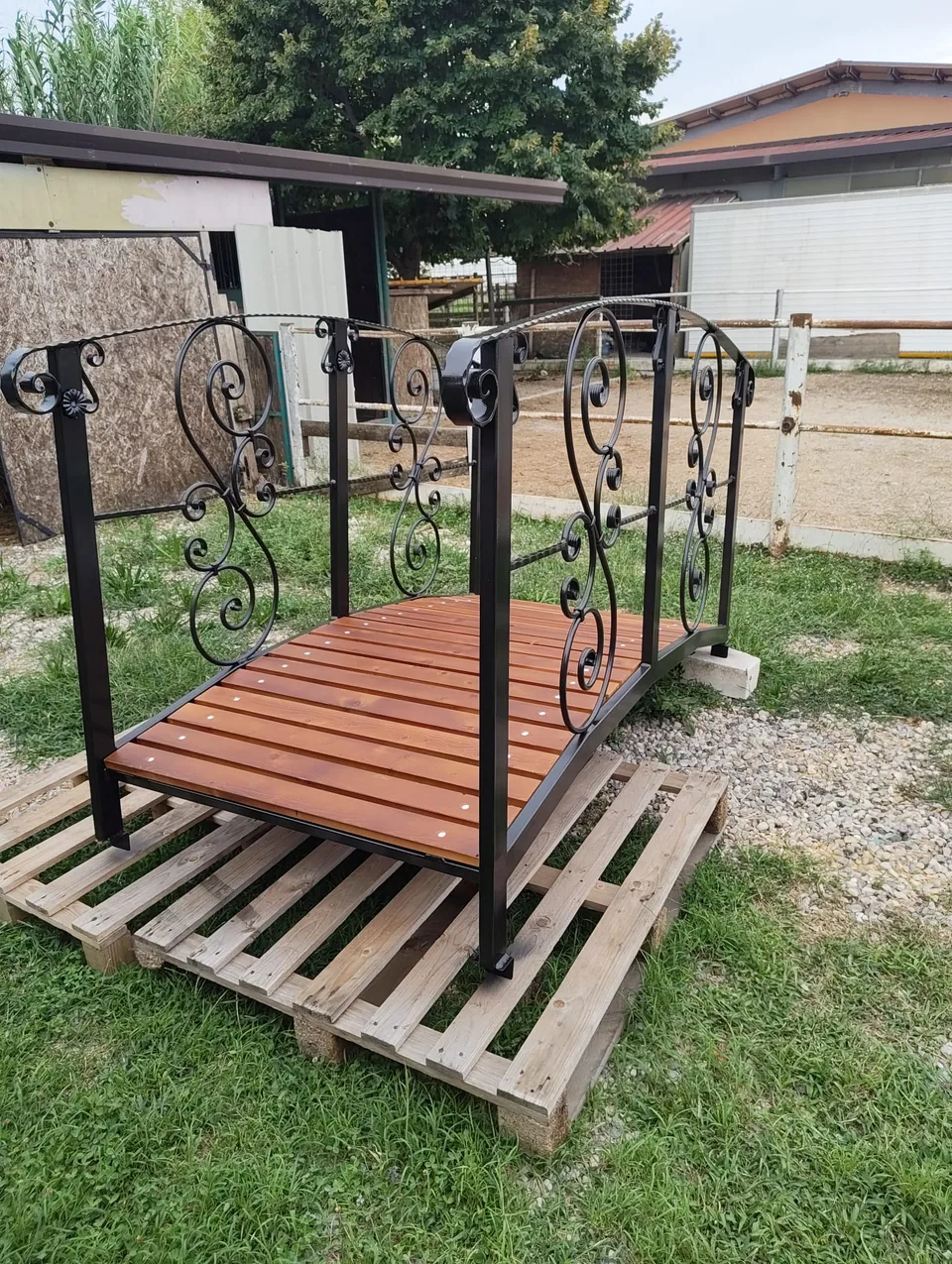 Wrought iron footbridge just completed, resting on pallets in the yard